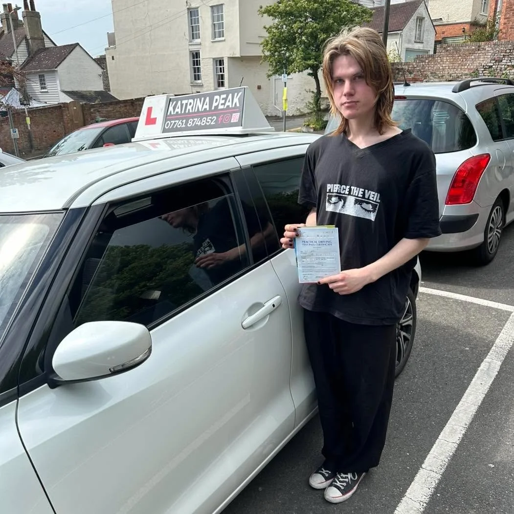 A pupil with their driving test pass certificate next to the Katrina Peak Driving School car